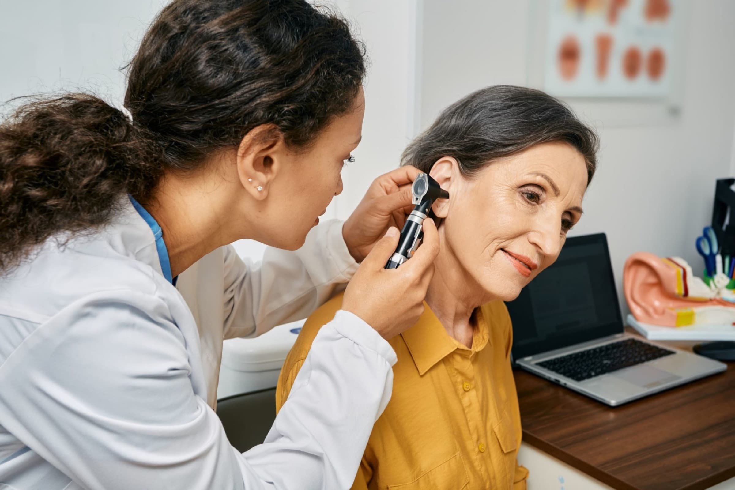 Clinician examining an ear with an otoscope